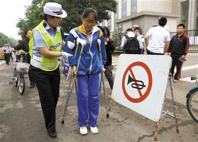 6月7日，东直门中学，一位考生拄着拐、在交警的搀扶下进考场。新京报记者 韩萌 摄