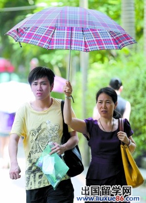 二十一中考场外，母亲为孩子撑起遮阳伞。