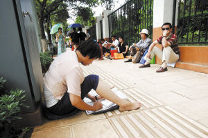 一名家长在昆八中外等待孩子考试时，赤脚坐在路边复习功课  张悦