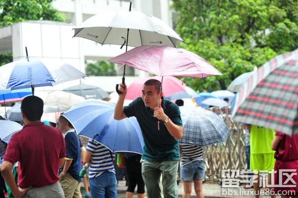2016年6月7日，广州市天河中学考点，考试临结束时，突降大雨，家长们撑着伞在考场外等候考生出来，没有带伞的考生们则用外套充当遮雨的器具。 视觉中国 图